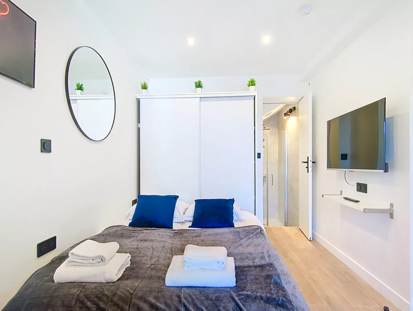 chambre lit tv location appartement argenteuil Chambre moderne avec lit, télévision et miroir.