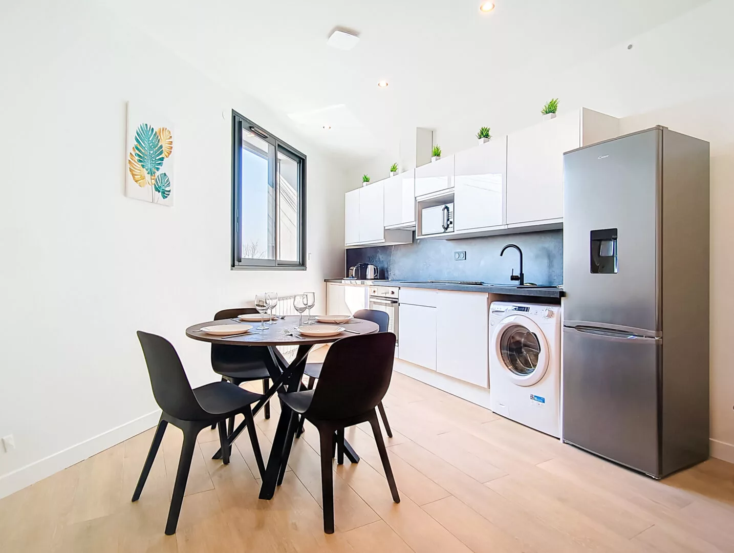 coin repas cuisine location appartement court sejour argenteuil Cuisine moderne avec réfrigérateur et table à manger.