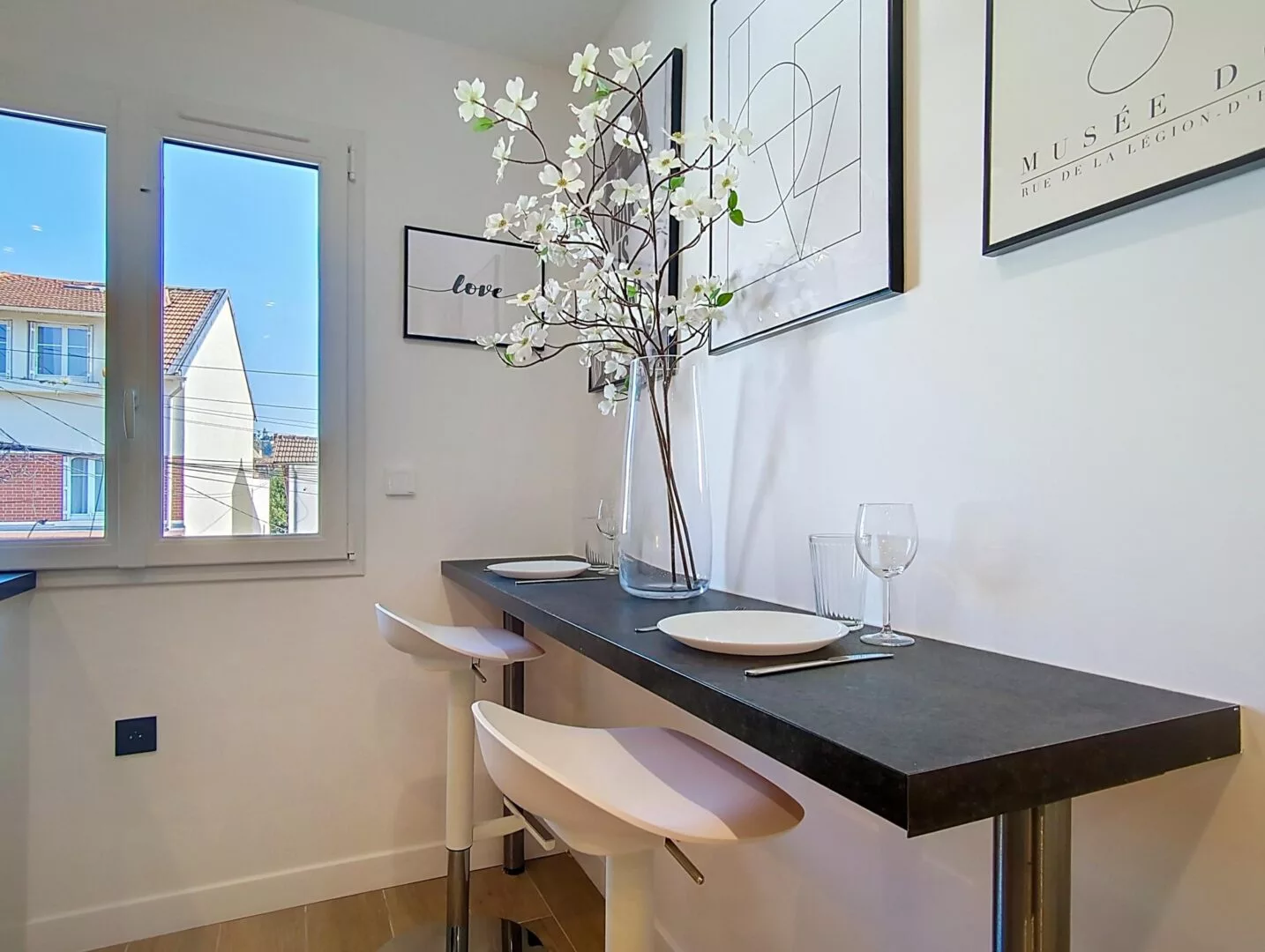 coin repas fenetre decoration location appartement argenteuil Coin repas moderne avec tabourets hauts et décoration florale.