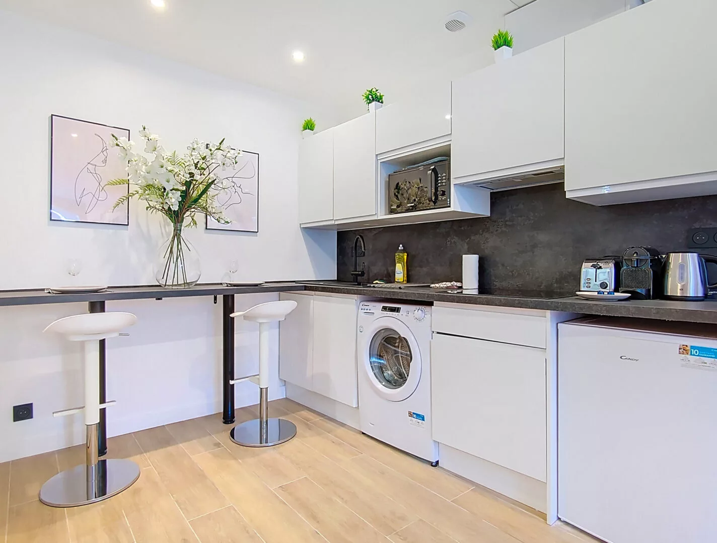 cuisine moderne avec comptoir et tabourets blancs location appartement argenteuil Cuisine moderne avec comptoir et appareils électroménagers.