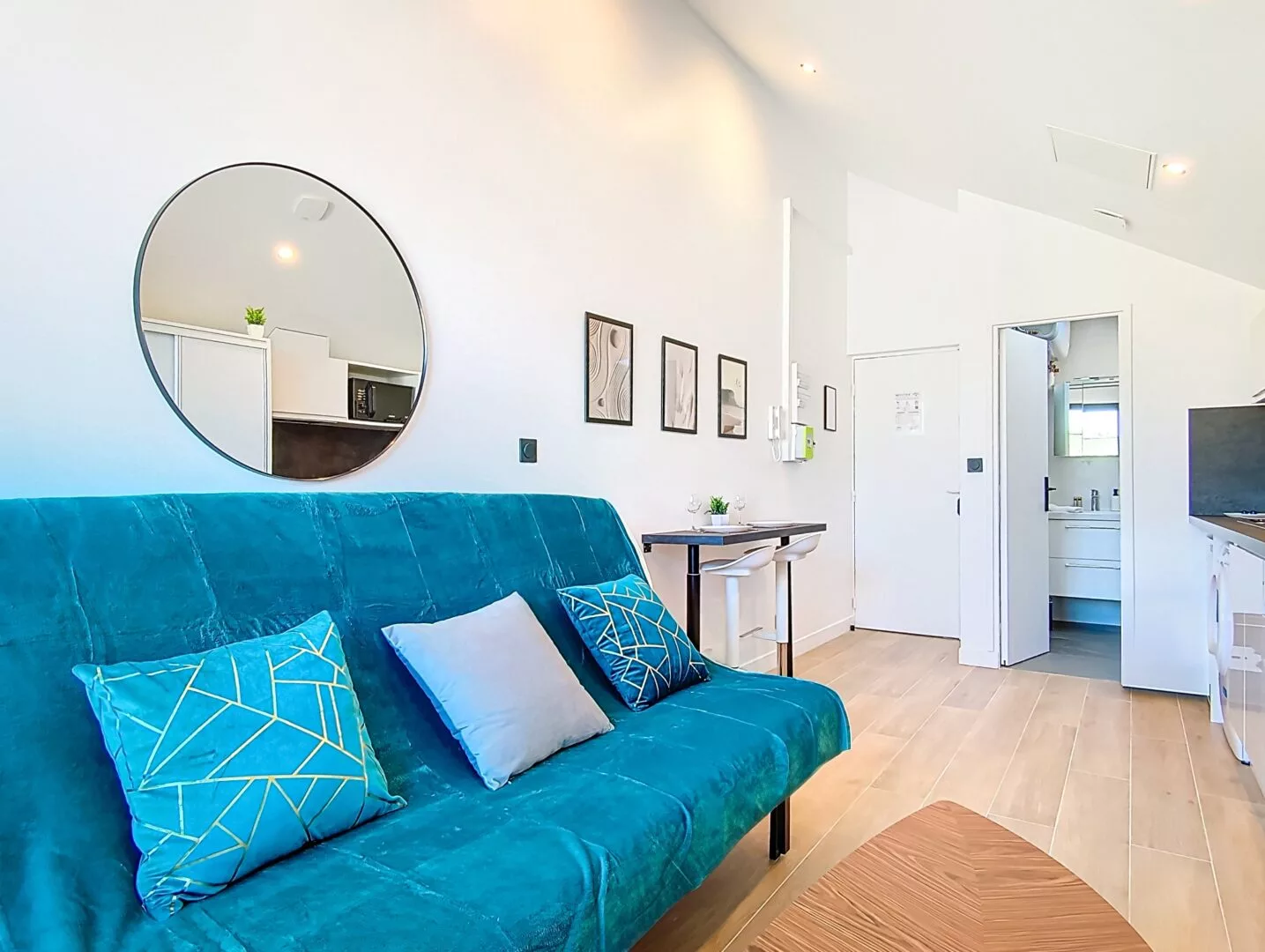 espace salon miroir rond location appartement court et long sejour argenteuil Salon moderne avec canapé turquoise et miroir rond.