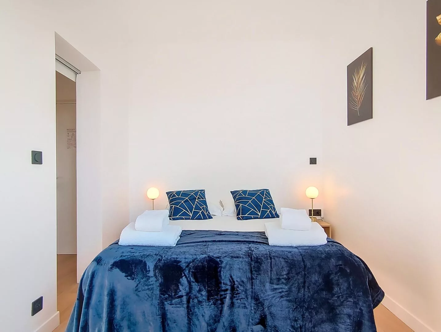 lit double avec decoration murale location appartement court sejour argenteuil Chambre moderne avec lit, décor bleu.