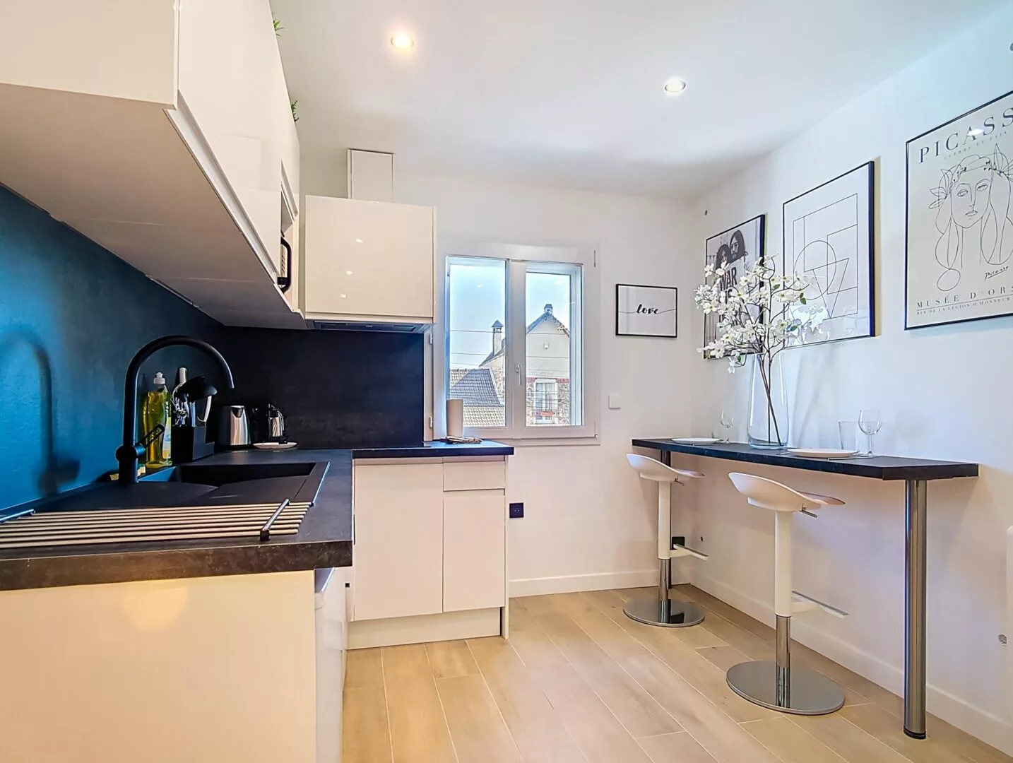 plan large cuisine salon location appartement argenteuil Cuisine moderne avec table haute et chaises blanches.