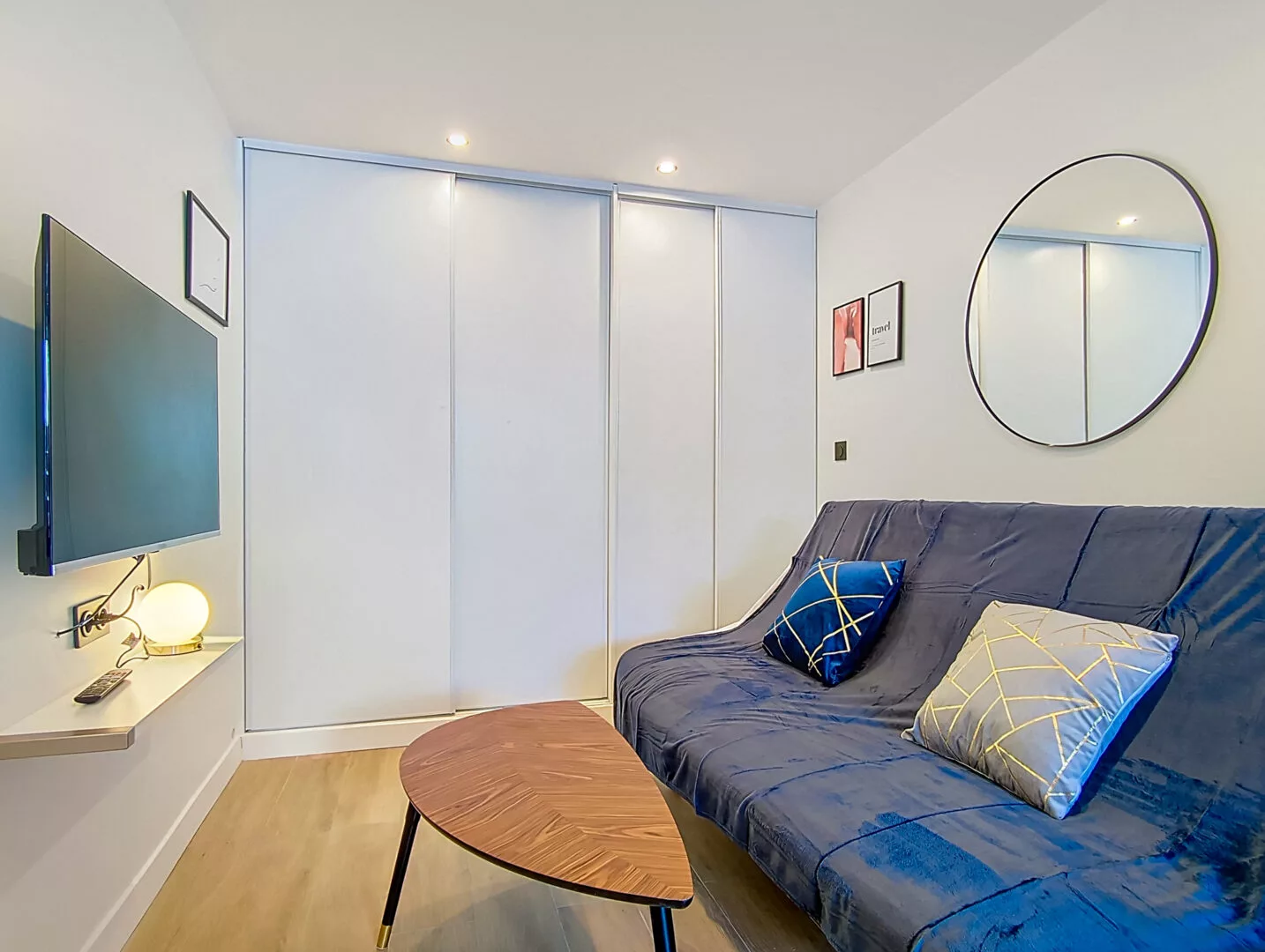 salon moderne avec canapé bleu, tv et miroir location appartement argenteuil Salon moderne avec canapé bleu et télévision.
