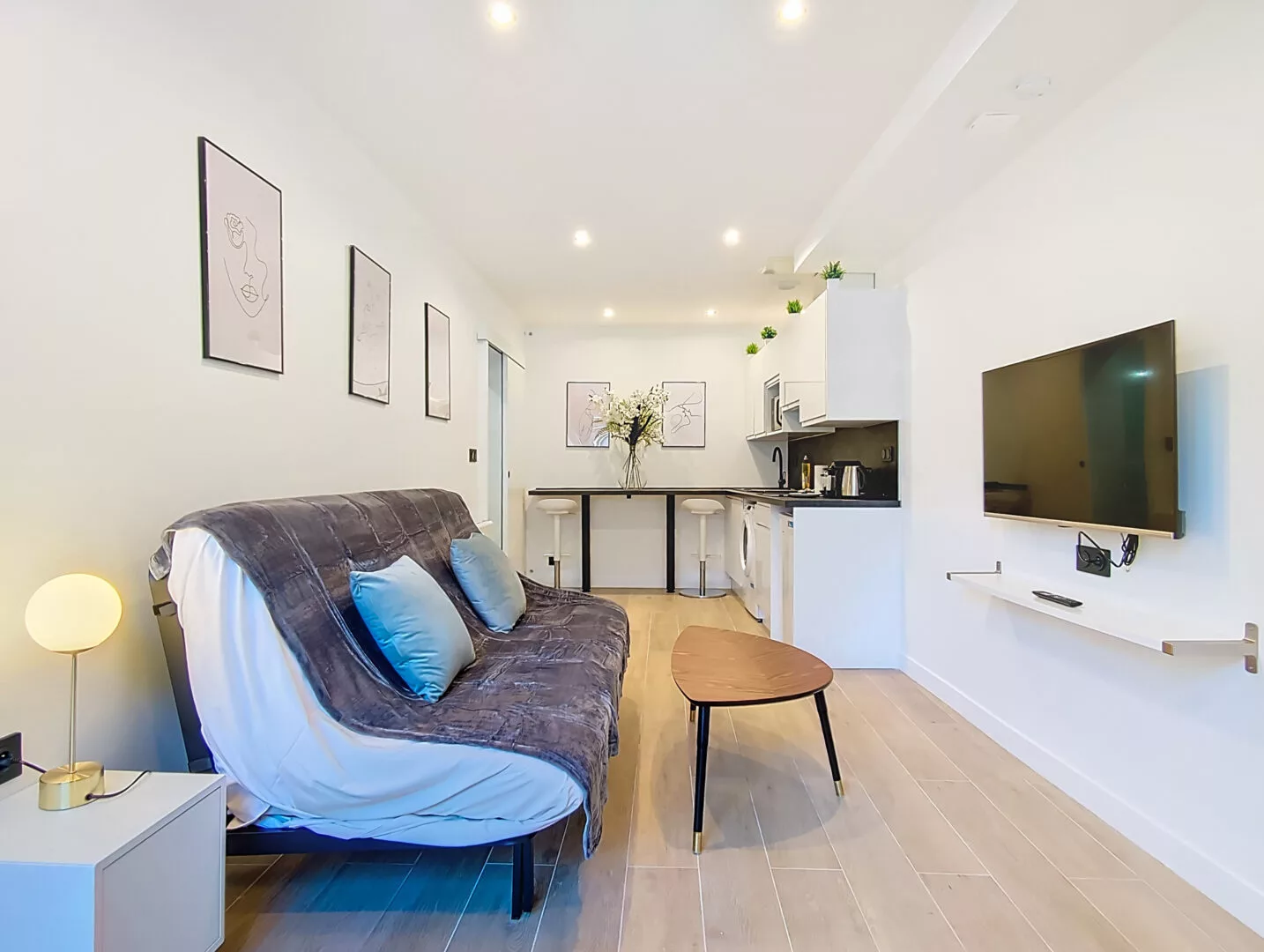salon moderne avec canapé et coin cuisine location appartement argenteuil Salon moderne avec canapé et télévision murale.