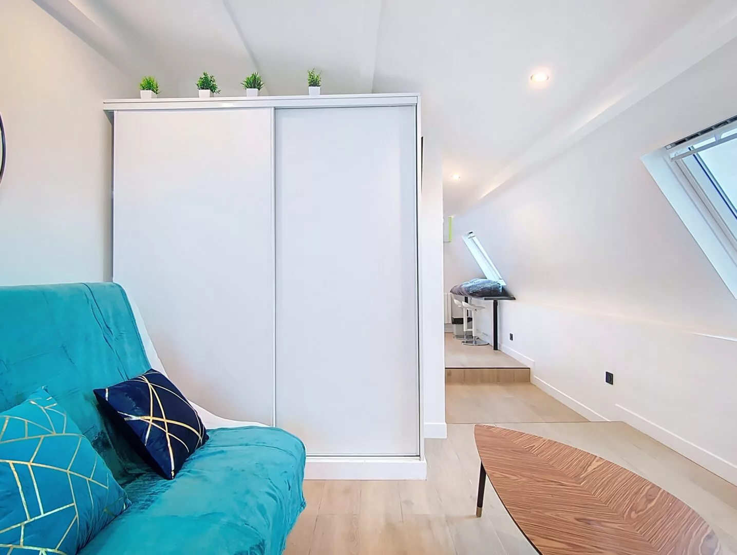 armoire appartement vie d'artiste argenteuil Salon moderne avec canapé turquoise et table basse.