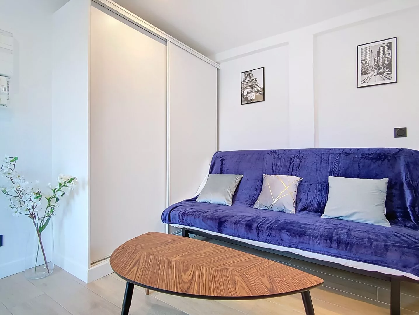 canapé location studio voyage argenteuil Salon moderne avec canapé bleu et table en bois.