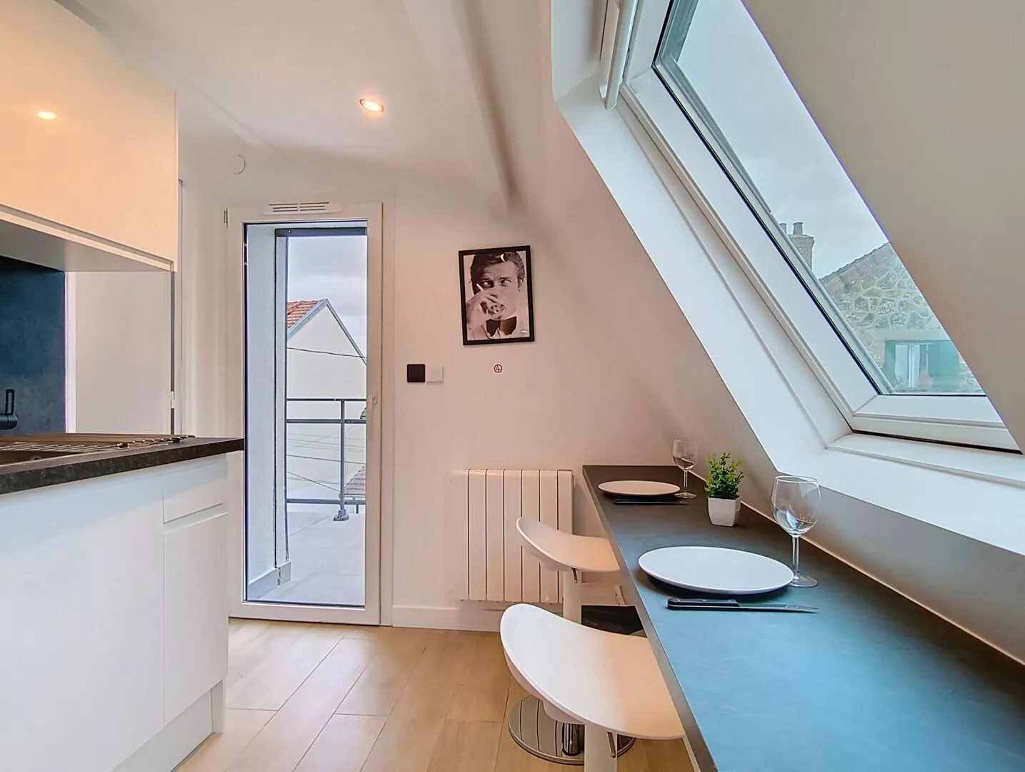 coin repas appartement vie d'artiste argenteuil Cuisine lumineuse avec table et tabourets dans grenier.