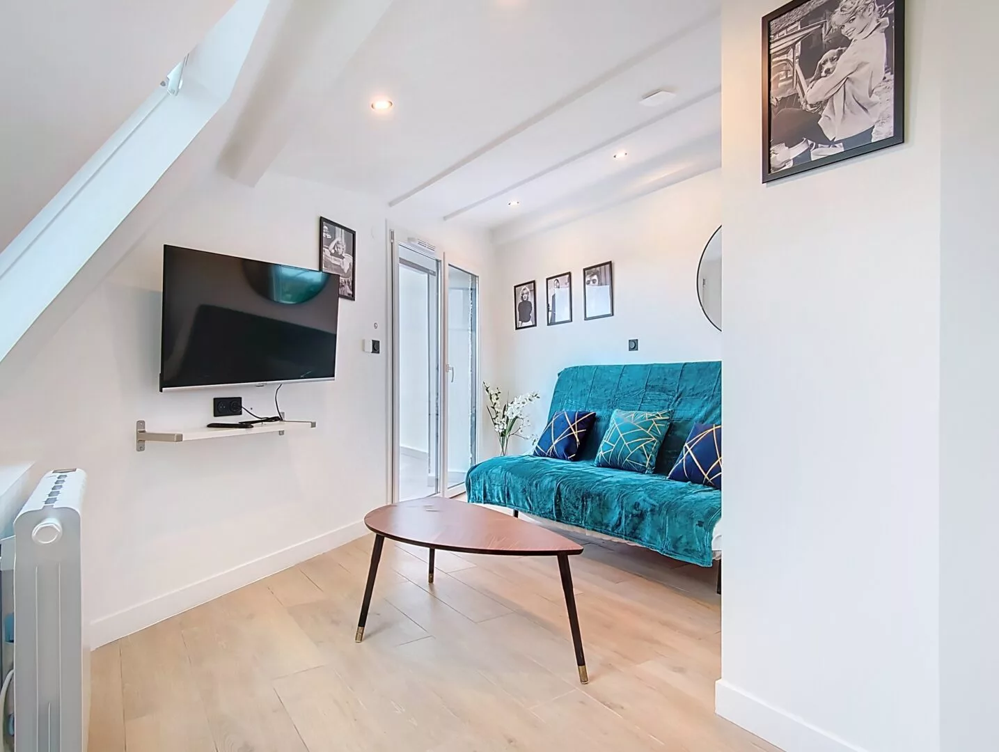 coin séjour appartement vie d'artiste argenteuil Salon moderne avec canapé bleu et télévision murale.