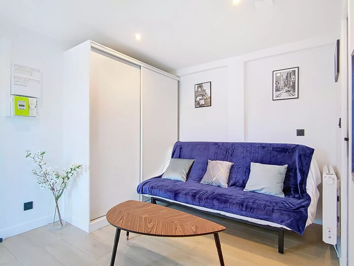 salon location studio voyage argenteuil Salon moderne avec canapé bleu et décorations murales.