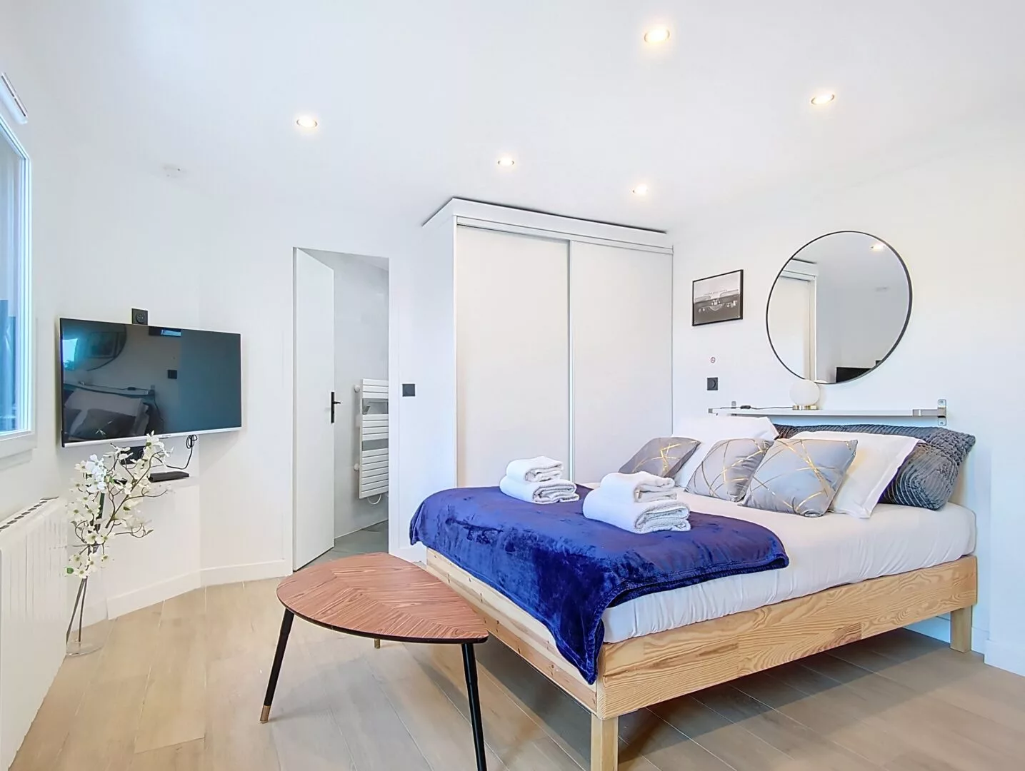 agencement studio argenteuil espace detente table basse Chambre moderne avec lit double, TV et miroir.