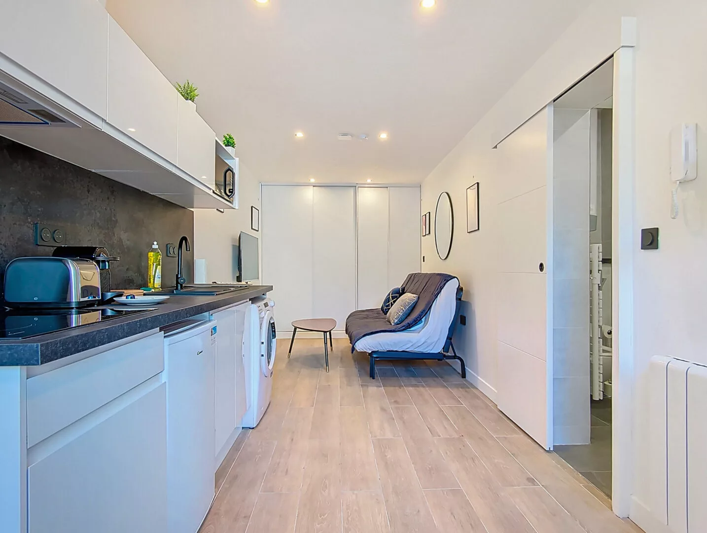 appartement moderne avec cuisine équipée et canapé lit location appartement argenteuil Petite cuisine moderne avec coin salon intégré.