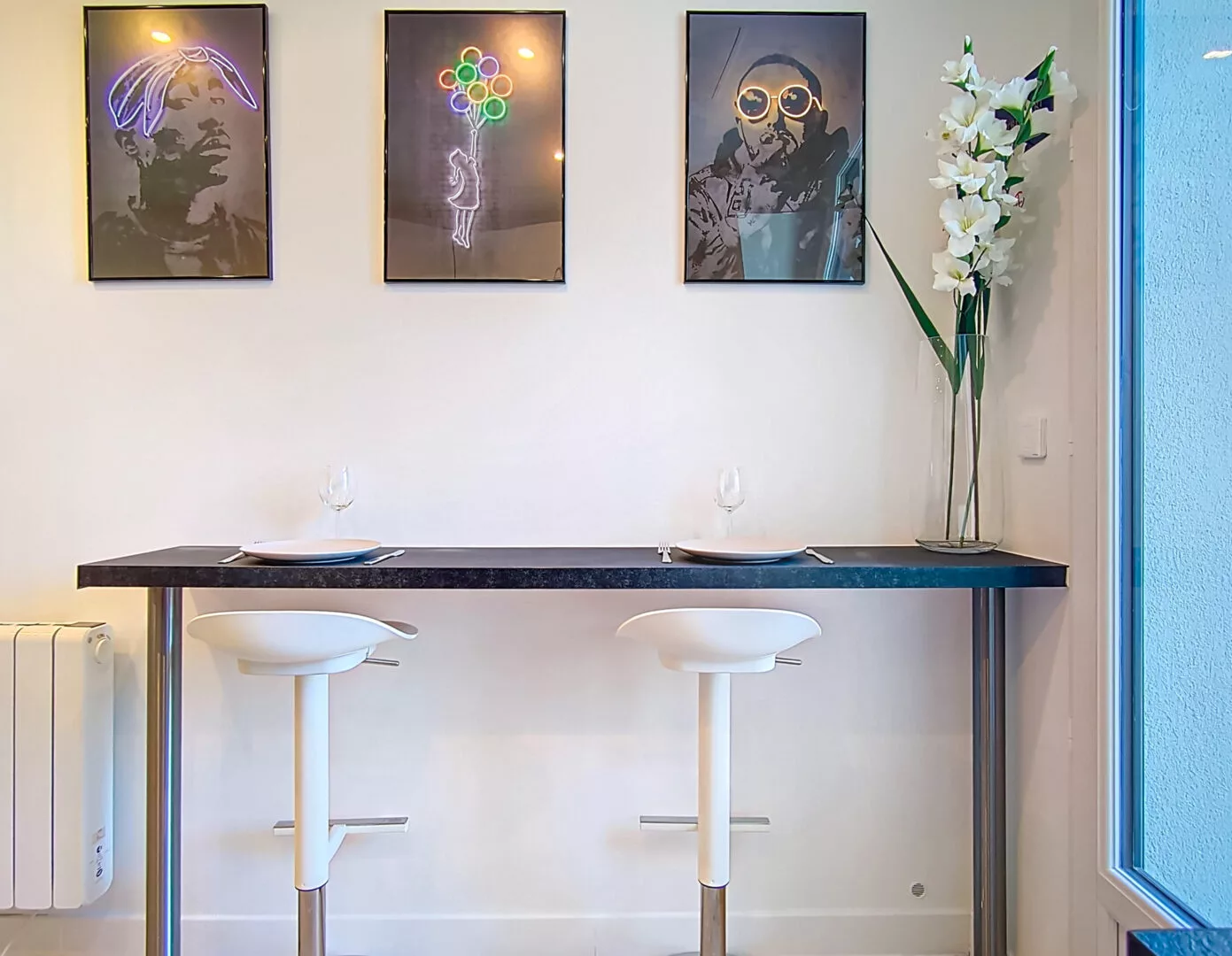 coin repas moderne location appartement argenteuil Cuisine moderne avec tabourets et tableaux muraux.