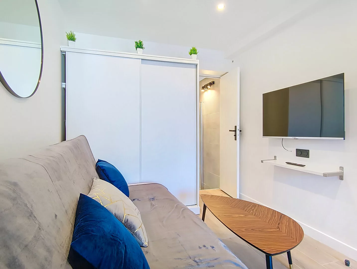 coin salon tv location appartement argenteuil Salon moderne avec canapé et télévision murale.