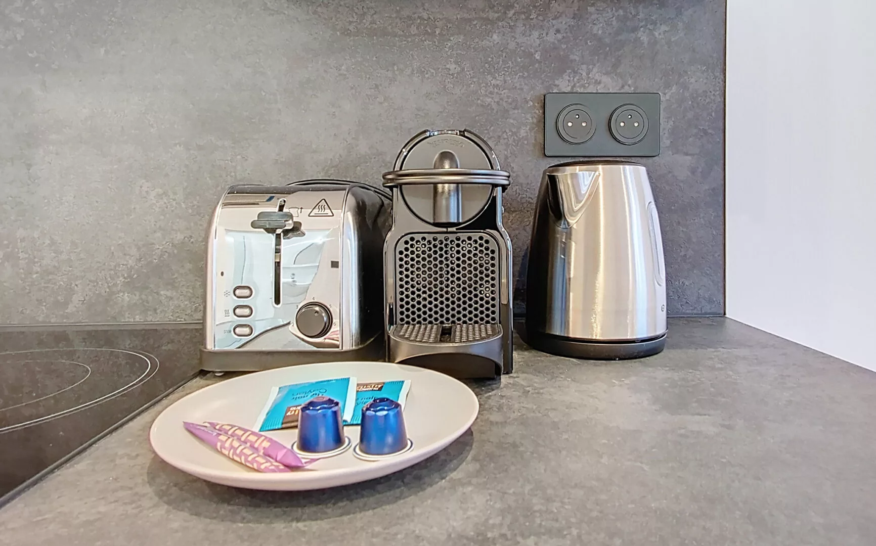 cuisine grille pain, cafetière, bouilloire et capsule location appartement argenteuil Appareils de cuisine avec dosettes de café sur comptoir.