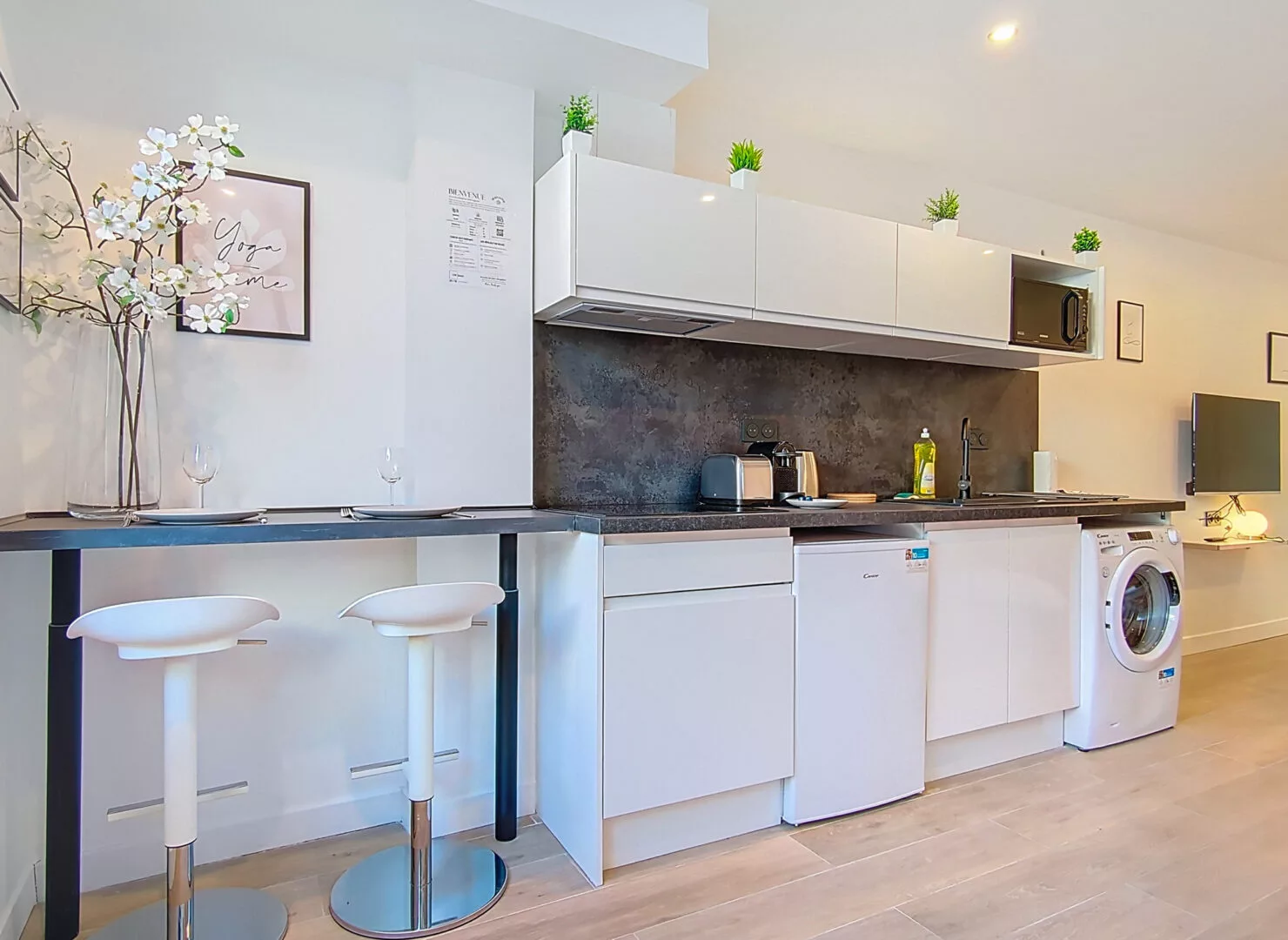 cuisine moderne avec électroménager et tabourets blancs location appartement argenteuil Cuisine moderne avec bar et appareils électroménagers.