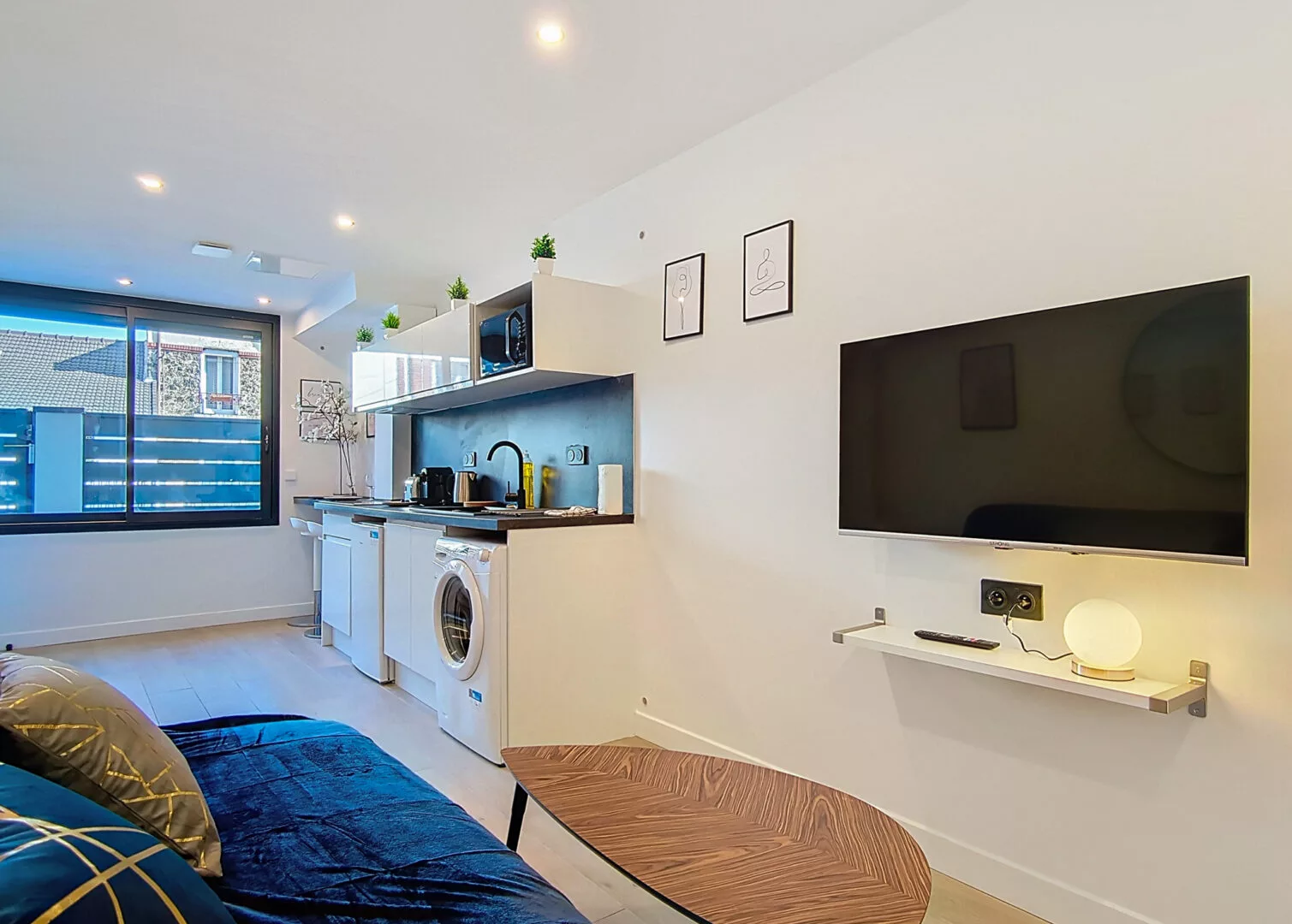 intérieur d'un appartement moderne et lumineux location appartement argenteuil Salon moderne avec cuisine équipée et télévision murale.