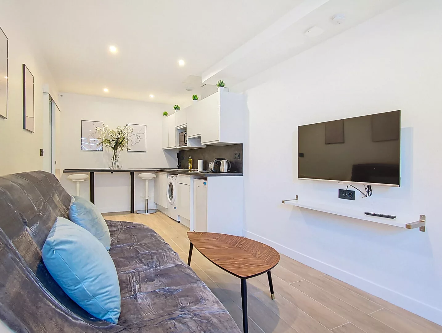 salon moderne avec canapé et télé location appartement argenteuil Salon moderne avec cuisine et canapé gris.