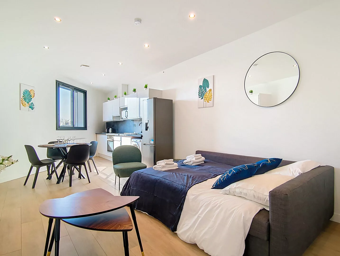 vue du salon lit location appartement court sejour argenteuil Studio lumineux avec cuisine intégrée.