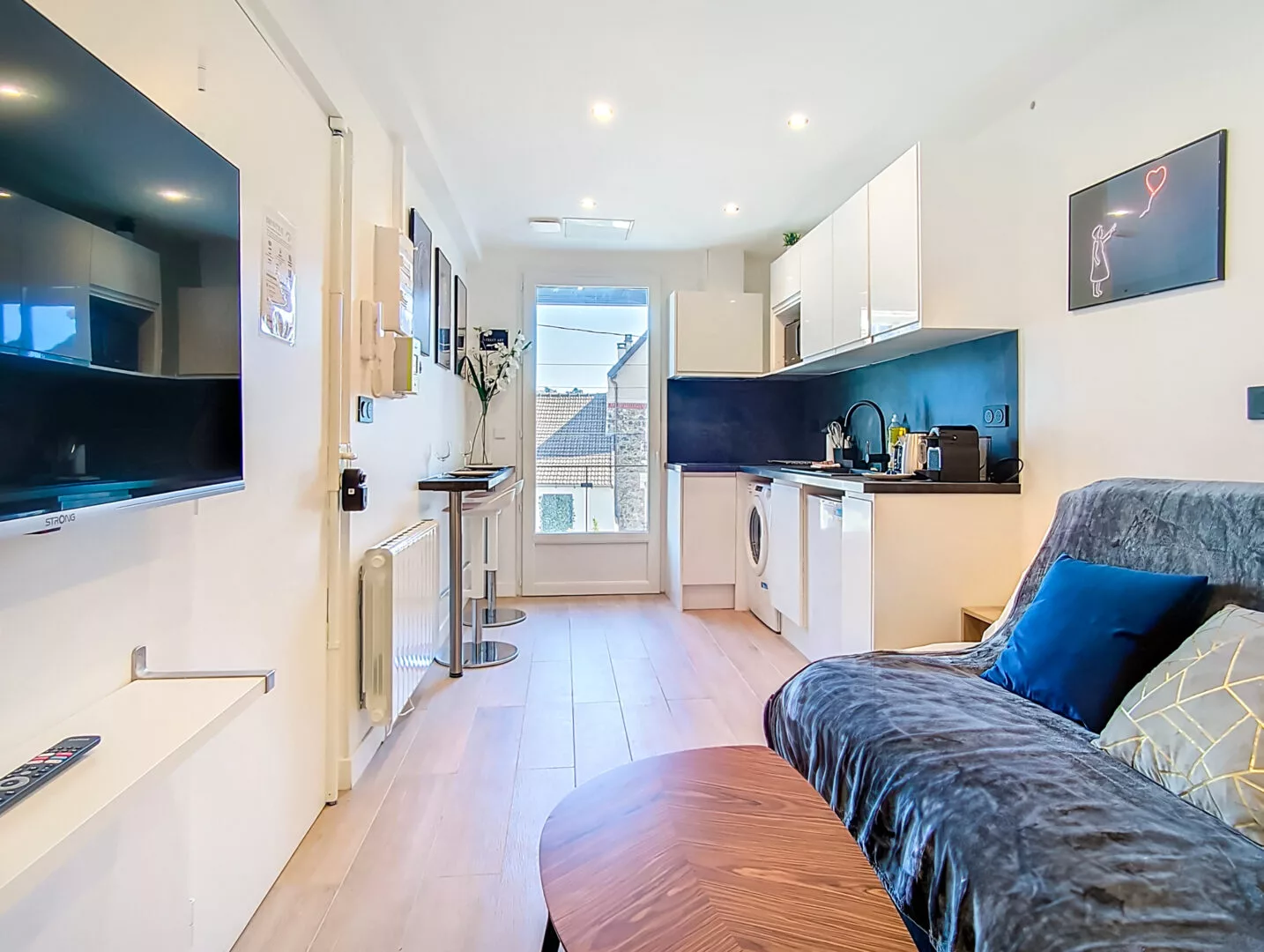 vue salon cuisine location appartement argenteuil Salon moderne avec cuisine intégrée et canapé.