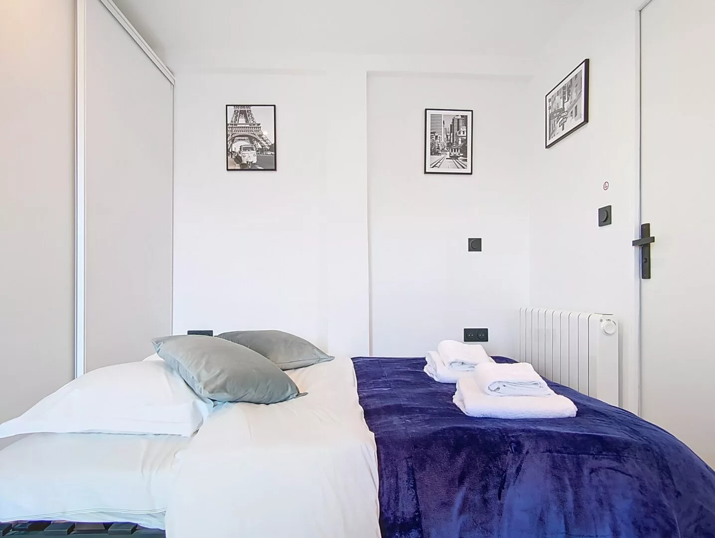 lit 2 personnes location studio voyage argenteuil Chambre moderne avec lit et décorations murales.