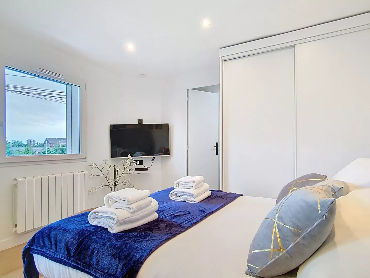 logement lumineux argenteuil couchage confortable Chambre moderne avec lit et télévision murale.